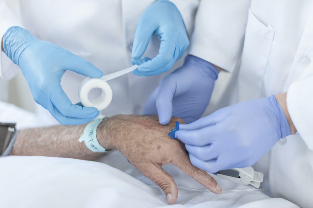 Nurse inserting IV needle in patients hand