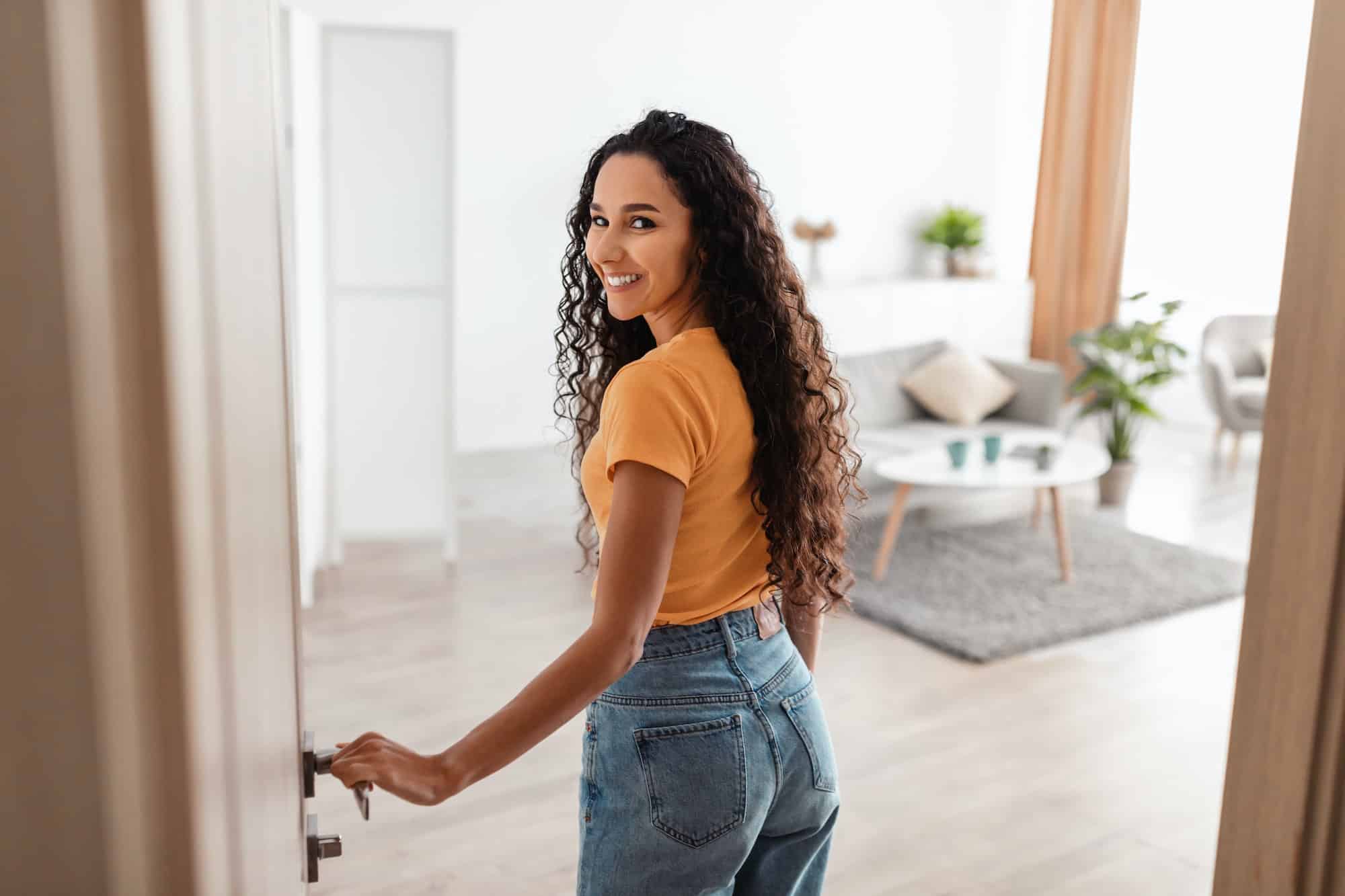Back view of excited young woman walking in apartment